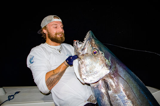 Douglas Dahlberg hÄller upp en dogtooth tuna fÄngad pÄ natten med Outside Travels