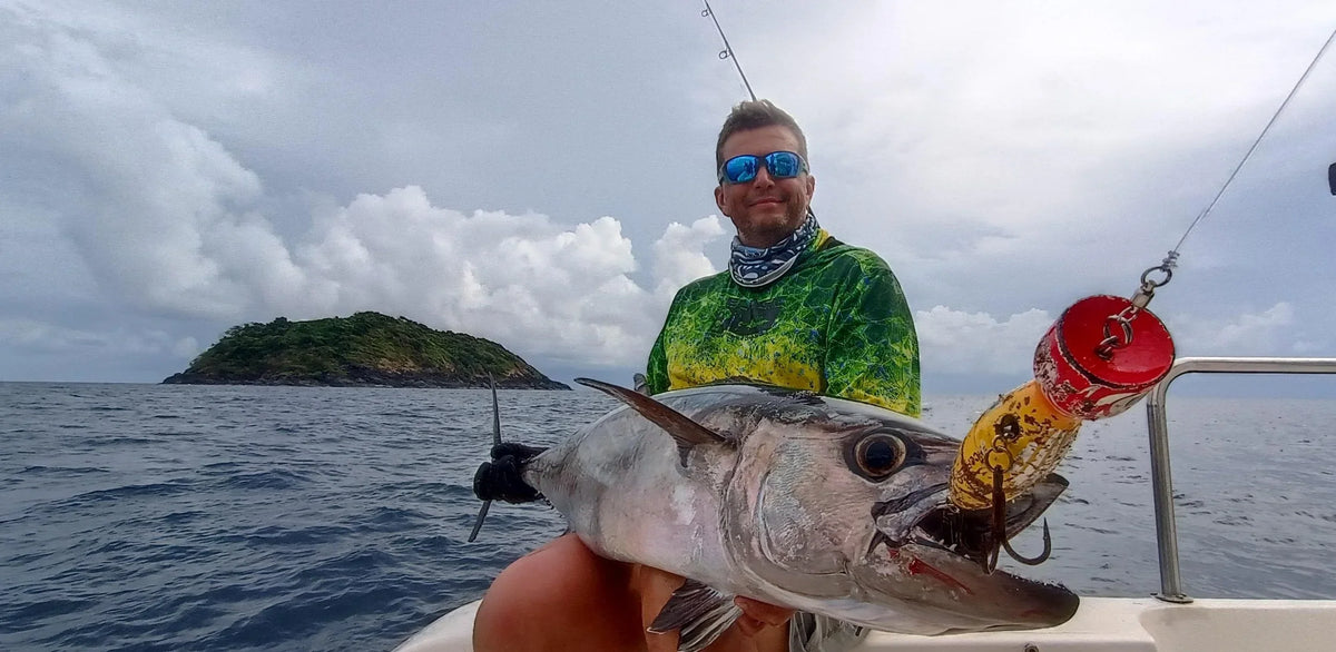 Sportfiskare håller en stor dogtooth tuna på båten utanför Andamanerna
