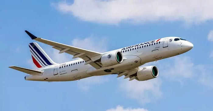 Ett passagerarflygplan från Air France flyger under en blå himmel med moln på väg till ett populärt resmål för fiskeresor. Ett vitt flygplan med blå, röda och vita ränder på stjärten.