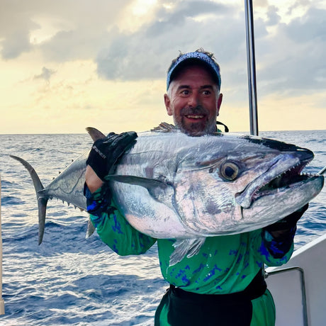 Sportfiskare med grönt mönstrad skjorta håller stor silverfisk på båt, Seychellerna popping- och jiggingresa.