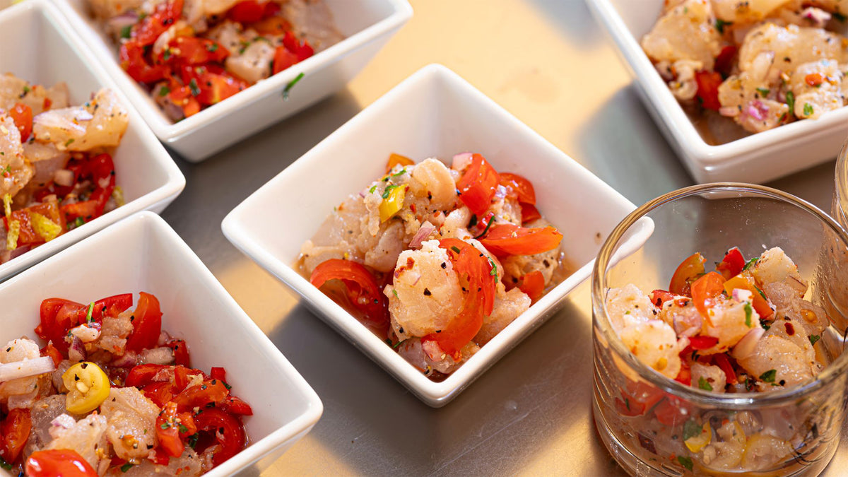 Flera små skålar med färgstark ceviche av fisk, tomat och örter på ljus yta - idealiskt för fiskeresa eller sportfiskare.