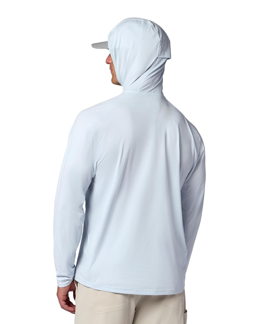 Man i ljusblå Simms Solarflex fiskehoodie med solskydd, beige byxor och keps visar ventilerande tyg mot vit bakgrund.