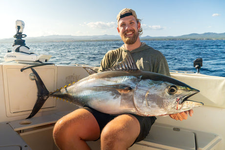 Leende fiskare med en blåfenad tonfisk i knät ombord på båten under en fiskeresa till Spanien